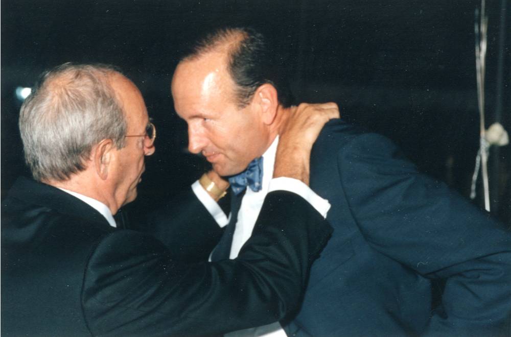 Richard DeVos putting his hands on Doug DeVos' shoulders and looking into his eyes.